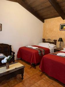 um quarto com duas camas com lençóis vermelhos e uma mesa em Hotel T KON T em Antigua Guatemala