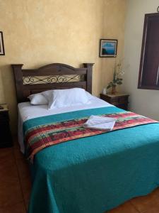 um quarto com uma cama com um cobertor azul em Hotel T KON T em Antigua Guatemala
