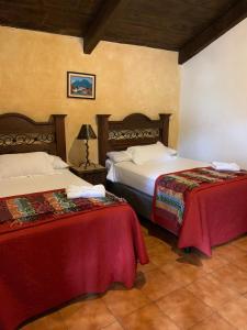 um quarto de hotel com duas camas com lençóis vermelhos em Hotel T KON T em Antigua Guatemala