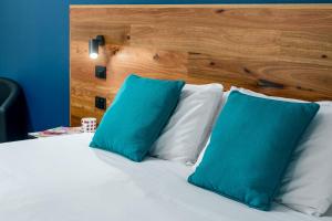 a bed with blue and white pillows and a wooden headboard at Hunter Studios - Maitland in Maitland