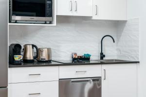 a white kitchen with a sink and a microwave at Hunter Studios - Maitland in Maitland