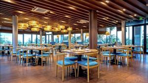 uma sala de jantar com mesas, cadeiras e janelas em Oceanami em Long Hai
