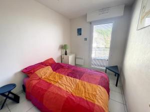 ein Schlafzimmer mit einem farbenfrohen Bett und einem Fenster in der Unterkunft Appartement Granville, 2 pièces, 2 personnes - FR-1-361-440 in Granville