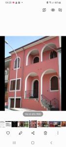 ein rosafarbenes Gebäude mit Fenstern und einem Balkon in der Unterkunft Affittacamere Su Padru in Ittiri