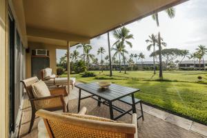 een patio met een tafel en stoelen en palmbomen bij The Olena at Keauhou Bay in Kailua-Kona
