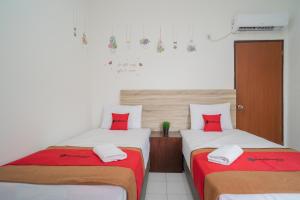 two beds in a room with red pillows on them at RedDoorz @ Glodok in Jakarta