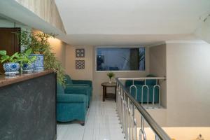 a living room with green chairs and a staircase at RedDoorz @ Glodok in Jakarta