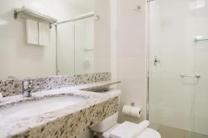 a bathroom with a toilet, sink, and mirror at Lagoon Prime Hotel in Lagoa Santa