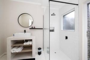 een badkamer met een douche, een wastafel en een spiegel bij 31OnGambia in Johannesburg