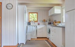 uma cozinha com armários brancos e um relógio na parede em 1 Bedroom Nice Home In Lyngdal em Lyngdal