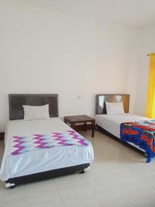 1 dormitorio con 2 camas y mesa en Tiu Kelep Homestay, en Senaru