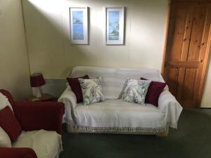 a living room with a white couch with pillows at Nuthatch Lodge is set in 24 acres of woodparkland near the village of Cenarth in Newcastle Emlyn