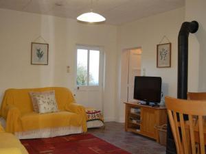 een woonkamer met een gele bank en een televisie bij Nestling in a beautiful setting on the edge of the Forest of Tronçais in Couleuvre