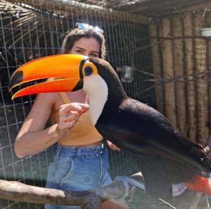 een vrouw met een grote oranje en zwarte vogel bij POUSADA e HOSTEL ARAUNA in Cabo Frio