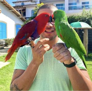 Een man houdt twee vogels op zijn hand. bij POUSADA e HOSTEL ARAUNA in Cabo Frio
