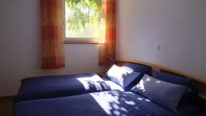 a bedroom with a bed with blue sheets and a window at Gasthof Hirschenbräu Michel in Rauhenebrach