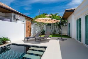 a patio with an umbrella and chairs next to a swimming pool at Orchid Paradise Homes OPV429 in Hua Hin