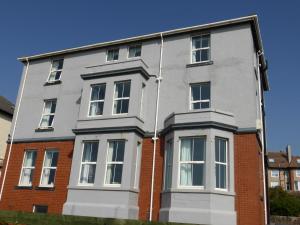 a grey building with white windows and a brick building at Bailey Ground Lodge in Seascale