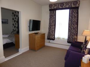 a living room with a tv and a bedroom at Bailey Ground Lodge in Seascale
