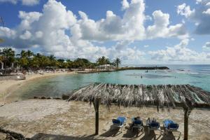 a beach with chairs and umbrellas and the ocean at Appartement Blue Lagon in Saint-François