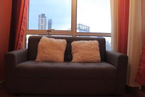 a couch with two pillows sitting in front of a window at A2J BGC Luxury 2BR Loft Near Burgos Circle, Malls in Manila