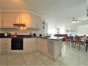 a kitchen with white cabinets and a dining room at Beachfront @ Driftwood 6 Luxury Family Apartment in Ballito