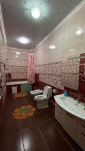 a bathroom with a toilet and a sink at Rosa Roze Luxe House in Karagandy