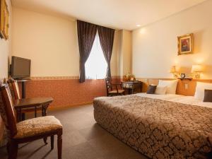 a hotel room with a bed and a desk and a tv at CHRES in Kochi