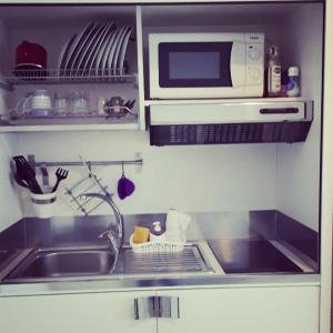 eine Küche mit einer Spüle und einer Mikrowelle in der Unterkunft Minisuite in Bologna