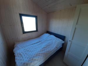 um pequeno quarto com uma cama e uma janela em Horyzont Bałtyku em Gąski