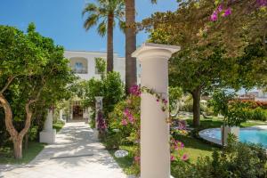 a column in a garden with flowers and a swimming pool at Pazziella Garden & Suites in Capri