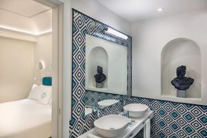 a bathroom with a mirror and two sinks and a bed at Pazziella Garden & Suites in Capri