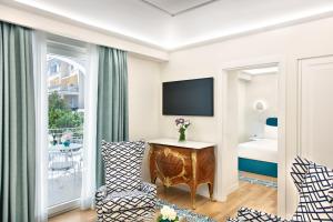 a hotel room with a bed and a tv and a chair at Pazziella Garden & Suites in Capri