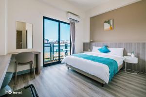 um quarto de hotel com uma cama, uma secretária e uma janela em Penghu Lemongrass em Magong