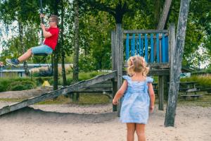 a little girl watching a young boy on a swing at Europarcs Zuiderzee in Biddinghuizen