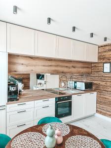 a kitchen with white cabinets and a wooden wall at Ranna Apartment in Võru