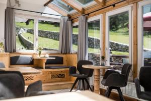 Zimmer mit Stühlen, Tischen und Fenstern in der Unterkunft Paradies Pure Mountain Resort in Sulden