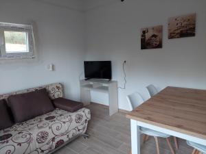 a living room with a couch and a table with a television at Apartments Dora, with a beautiful view of the bay, near the sea and center in Vrboska