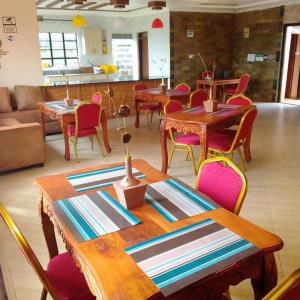 a dining room with wooden tables and chairs at Stay.Plus Villa Serene Kitale in Kitale