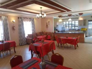 a restaurant with red tables and chairs and a kitchen at Stay.Plus Villa Serene Kitale in Kitale