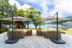 a patio with couches and two umbrellas at Hakone Hotel in Hakone