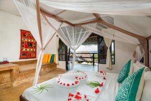 a bedroom with a white bed with red flowers on it at Sunshine Bay Hotel Zanzibar in Matemwe