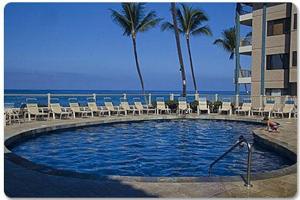 a swimming pool with chairs and the ocean in the background at New! Kona Reef Resort Oceanfront 2 Bdrm, 2 Bath D-11 Right on the Ocean! Casago Kona in Kailua-Kona