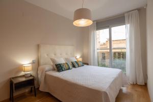 a white bedroom with a bed and a large window at Apartamento Bulevar 1 in Castellón de la Plana