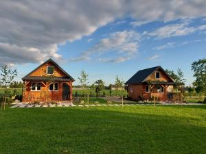 twee houten huizen in een veld met een groen gazon bij BLISKO NATURY - domki wypoczynkowe w Dolinie Baryczy in Milicz