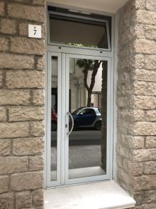 une porte coulissante en verre reflétant une voiture dans l'établissement Guido's City Rooms, à Alghero