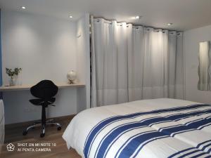 a bedroom with a bed and a chair and a window at Appartement de charme en plein coeur de Bergerac in Bergerac