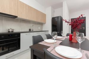 a kitchen with a dining table with wine glasses at Stacja Wola Apartment Gumińska by Renters in Warsaw