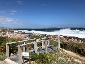 a wooden staircase leading to the ocean with waves at Whale Rock Estate Hermanus sea view apartment in Hermanus