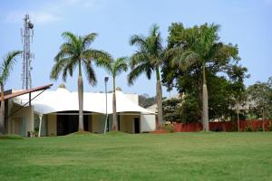 a building with palm trees in front of a field at The Dukes Retreat in Lonavala